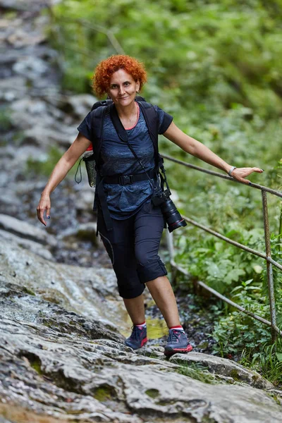 中年女性ハイカーが昼間に歩いています 山の道でハイキングのバックパックを持つ女性 — ストック写真