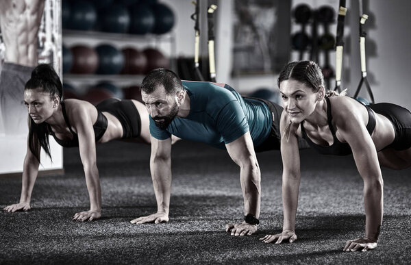 Athletic people doing crossfit training with trx straps