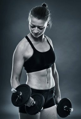 Genç kadın pazı kıvırmak yapıyor dumbbells ile yerleştirmek.