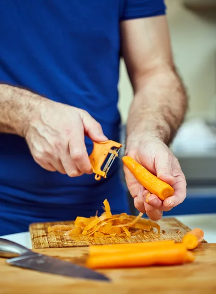 Man Peeling Carrots Wooden Board — Stock Photo, Image