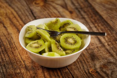 Taze Kivi Meyve bir kase bir ahşap tahta üzerinde dilimlenmiş