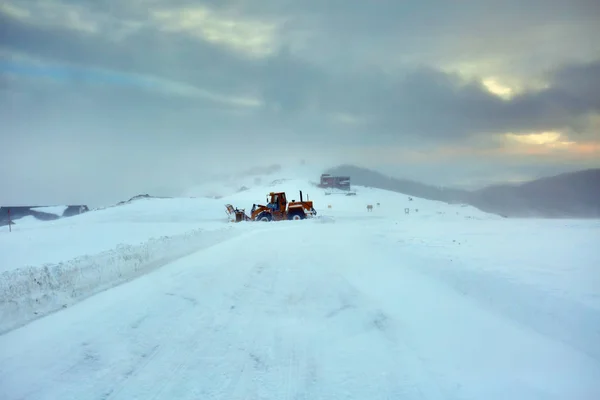 大拖拉机吹雪机清理山中的道路 — 图库照片