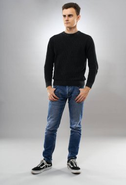 Kot pantolon ve kazak gri arka plan üzerine Trendy genç adam