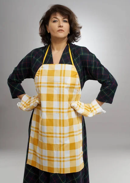 Housewife with apron and cooking gloves over gray background