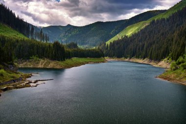 Yağmurlu bir günde dağların arasında bir göl ile manzara
