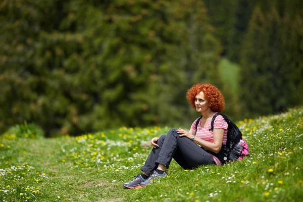 Lockige Rothaarige Frau Mit Rucksack Wandert Tagsüber Auf Wanderwegen lizenzfreie Stockbilder