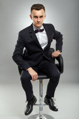 Genç işadamı iskemlede, gri arka plan