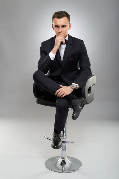 Jovem Empresário Sentado Cadeira Fundo Cinza — Fotografia de Stock