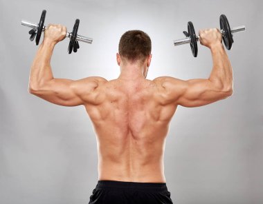 Gri zemin üzerine ağırlıklar ile çalışma dışarı fitness modeli