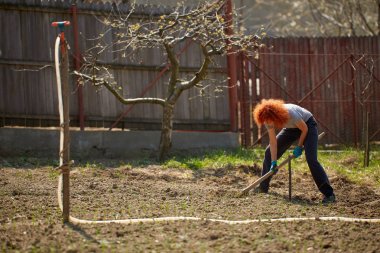 Çapayla bahçe işi yapan bir kadın.