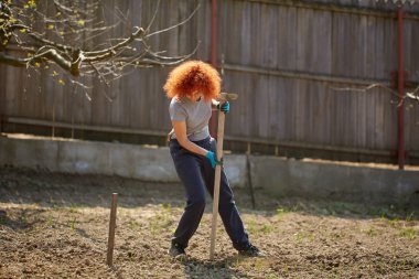 Çapayla bahçe işi yapan bir kadın.