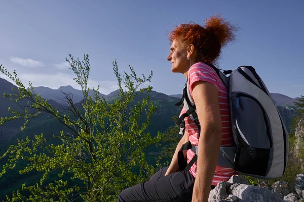 夕暮れ時に山の頂上にバックパックを持つ女性 — ストック写真