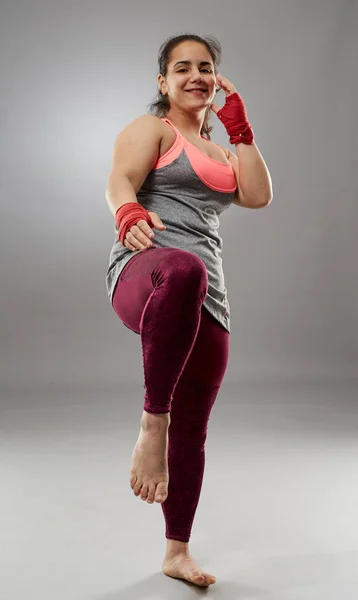 Young kickboxing female fighter in hand wraps, barefoot