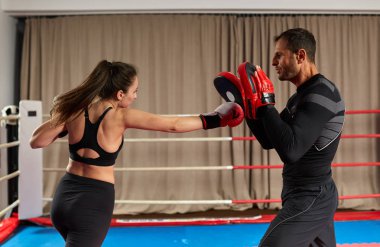 Genç bayan boksör ve koçu ringde yumruk tokuşturuyor.