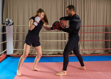 Genç bayan boksör ve koçu ringde yumruk tokuşturuyor.