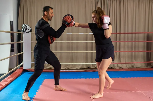 Genç bayan boksör ve koçu ringde yumruk tokuşturuyor.