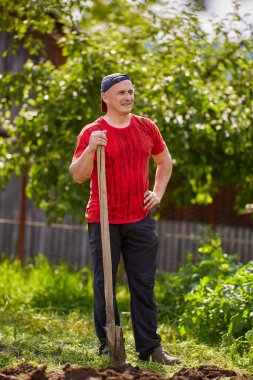 Çiftçi bahçesinde bir kürek ile çalışıyor