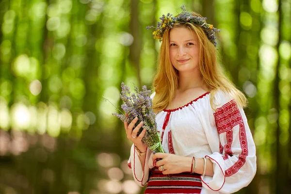 森の中でラベンダーの花束を持つ伝統的な衣装を着たルーマニアの少女の肖像 — ストック写真