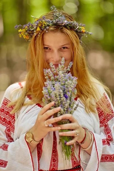 Ormanda lavanta buketi tutan geleneksel kostümlü Romen bir kızın portresi