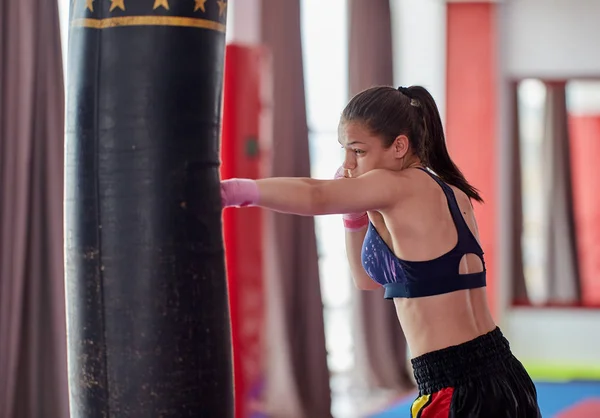 Kick-boxer female training at heavy bag with her hands wrapped