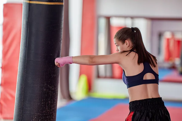彼女の手を包んだ重いバッグでキックボクサーの女性トレーニング — ストック写真