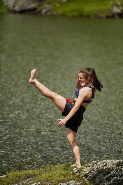 昼間の山の湖でキックボクサーの女の子の訓練 — ストック写真