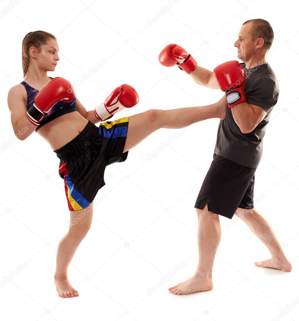 Young female kickboxer sparring with her coach on white background