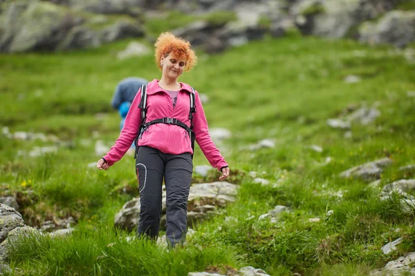 女人背着背包在岩石山脉的小径上徒步旅行 — 图库照片
