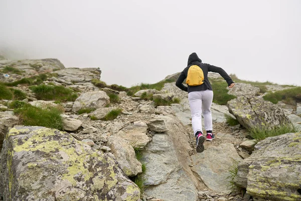 背着背包在岩石山上的小径上徒步旅行的女人 — 图库照片