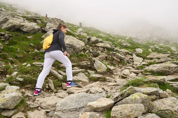岩の多い山のトレイルでバックパックハイキングを持つ女性 — ストック写真