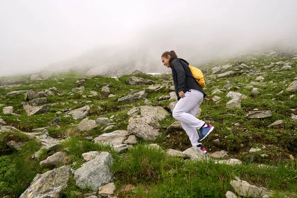 背着背包在岩石山上的小径上徒步旅行的女人 — 图库照片