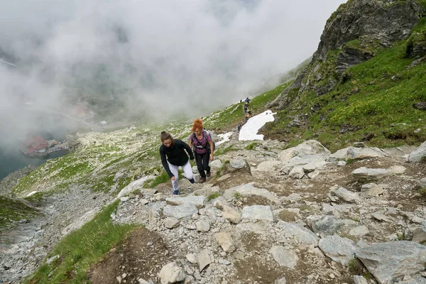 妇女背着背包在白天在岩石山脉的小径上徒步旅行 — 图库照片