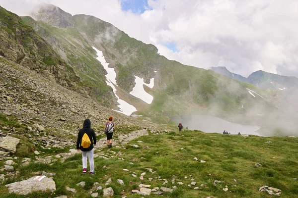 妇女背着背包在白天在岩石山脉的小径上徒步旅行 — 图库照片