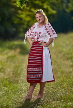 Portrait of a Romanian girl in traditional costume in an oak forest clipart