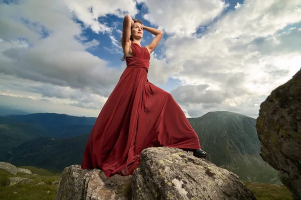 美丽的女性时装模特在山岩上的红色礼服 — 图库照片