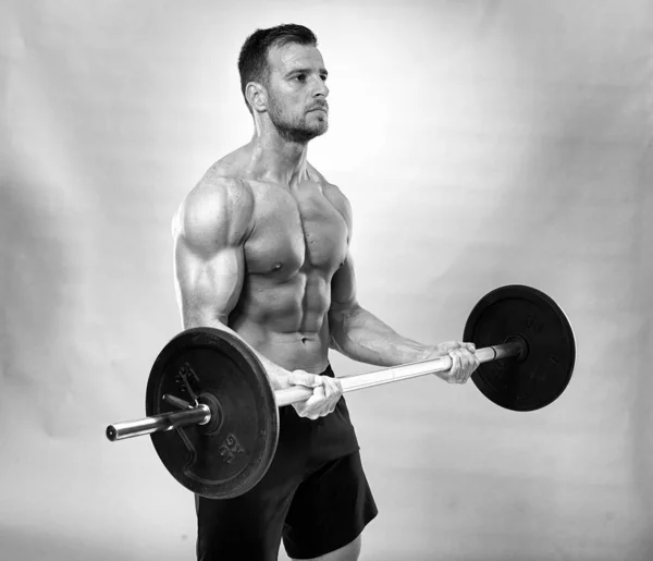 Man doing biceps curl with barbell in studio