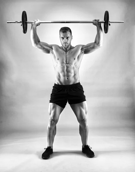 男人做肩部锻炼与杠铃灰色背景 — 图库照片