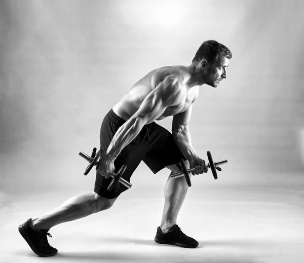 Fitness model working out with weights on gray background