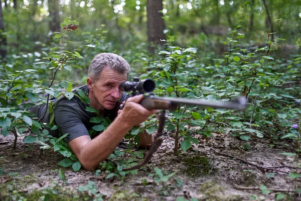 Hunter with rifle in the forest