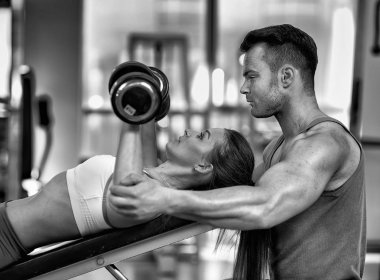 ağır dumbbells ile spor salonunda çalışan kadın yardımcı antrenör