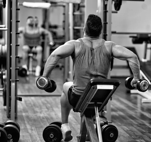 做肩部和背部锻炼在健身房里对着镜子的男人 — 图库照片