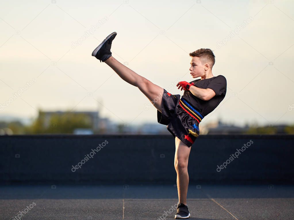 Young muay-thai fighter or kick-boxer training on the roof above the city