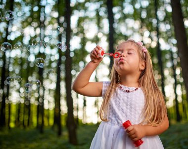 küçük kız ormanda sabun köpüğü üfleme