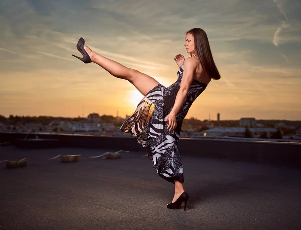 Beautiful strong woman with kickboxing moves in an elegant dress