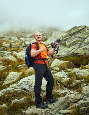 Bir dağ yolu üzerinde kamera ve sırt çantası yürüyüş ile Adam
