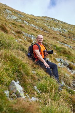 Bir dağ yolu üzerinde kamera ve sırt çantası yürüyüş ile Adam