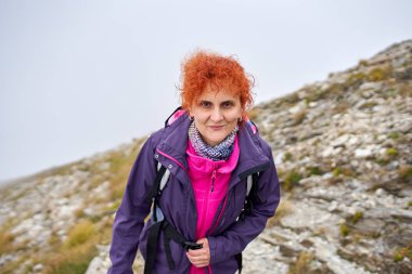 Sırt çantalı bir kadın dağ yolunda yürüyüş yapıyor.