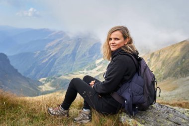 Sırt çantalı bir kadın dağ yolunda yürüyüş yapıyor.