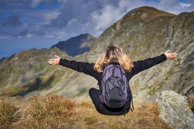 Sırt çantalı bir kadın dağ yolunda yürüyüş yapıyor.