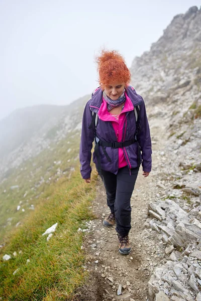 背着背包在山路上远足的女人 — 图库照片